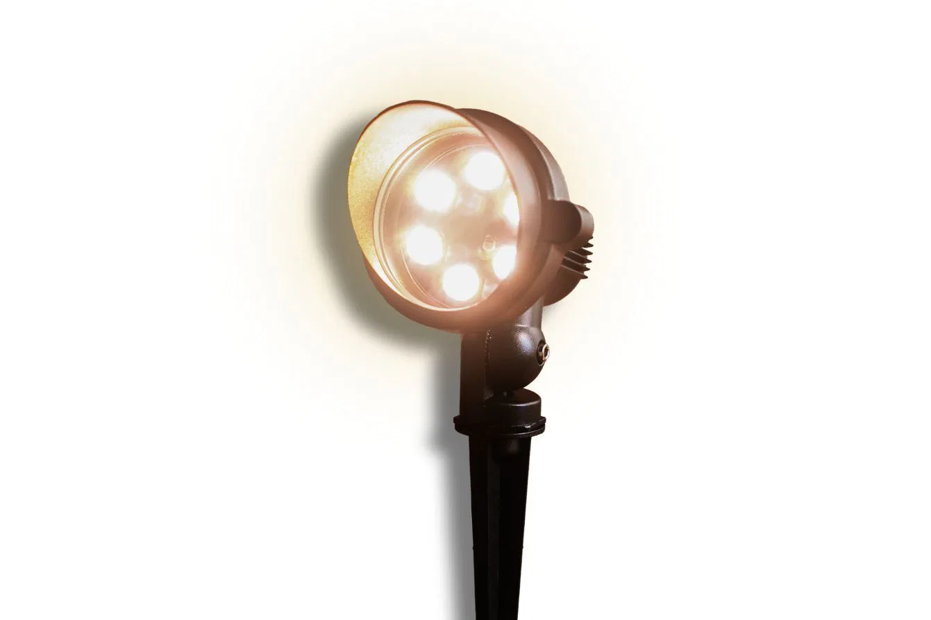 A black outdoor spotlight with five bright LED bulbs is mounted on a stake, casting a warm beam of light against a white background.