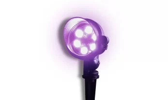 A black spotlight with four bright purple LED lights shines against a white background, casting a violet glow.